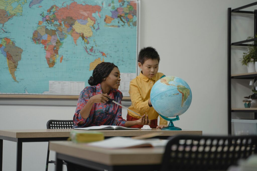 Teacher and student engaging with a globe in a classroom setting.